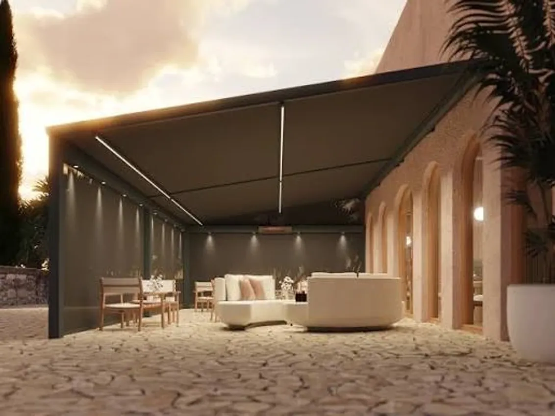 Grossflächiges Textildach B128 XL über einer Terrasse mit Lounge an einem mediterranen Haus in der Dämmerung