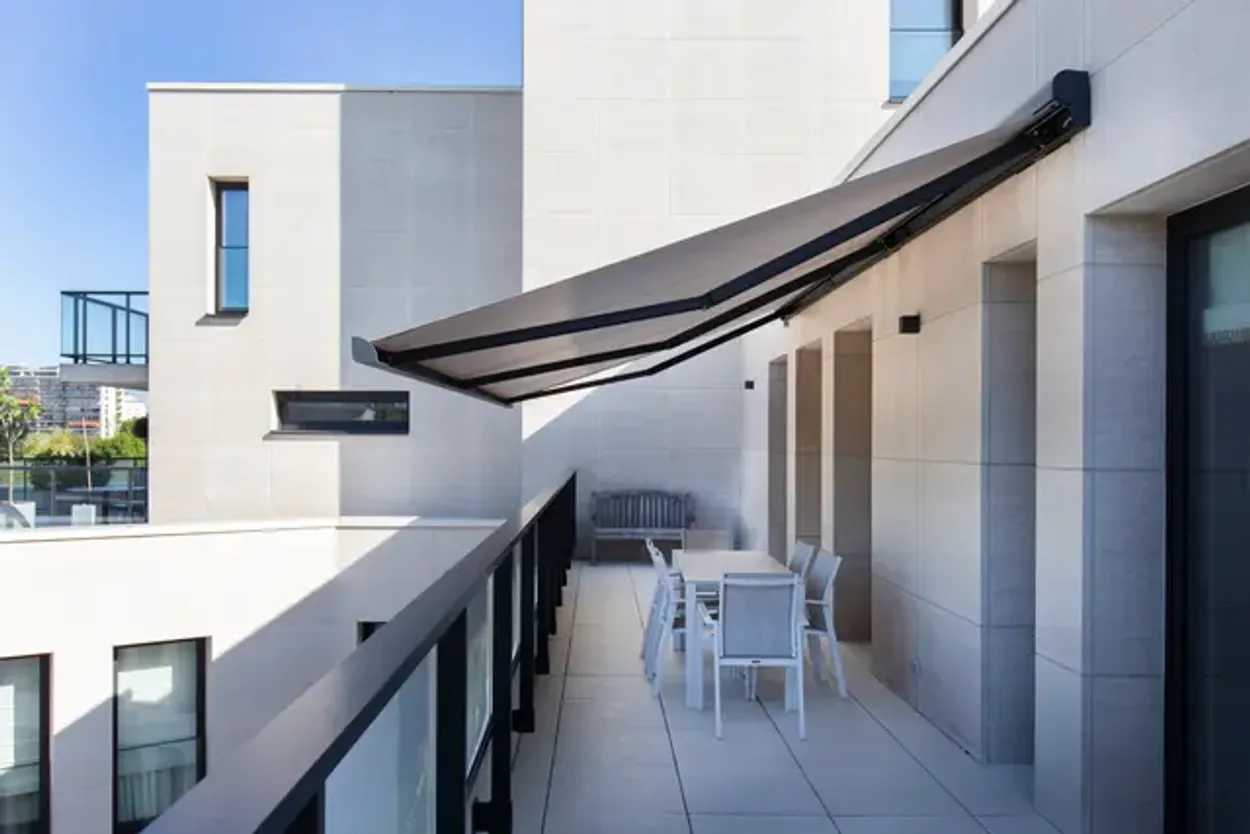 Dieselbe Dachterrasse im Schatten der ausgefahrenen Markise über dem Essplatz