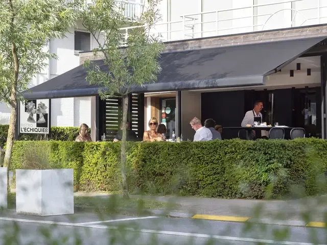 Markise B35 über einer Restaurantterrasse mit Gästen, davor eine Hecke
