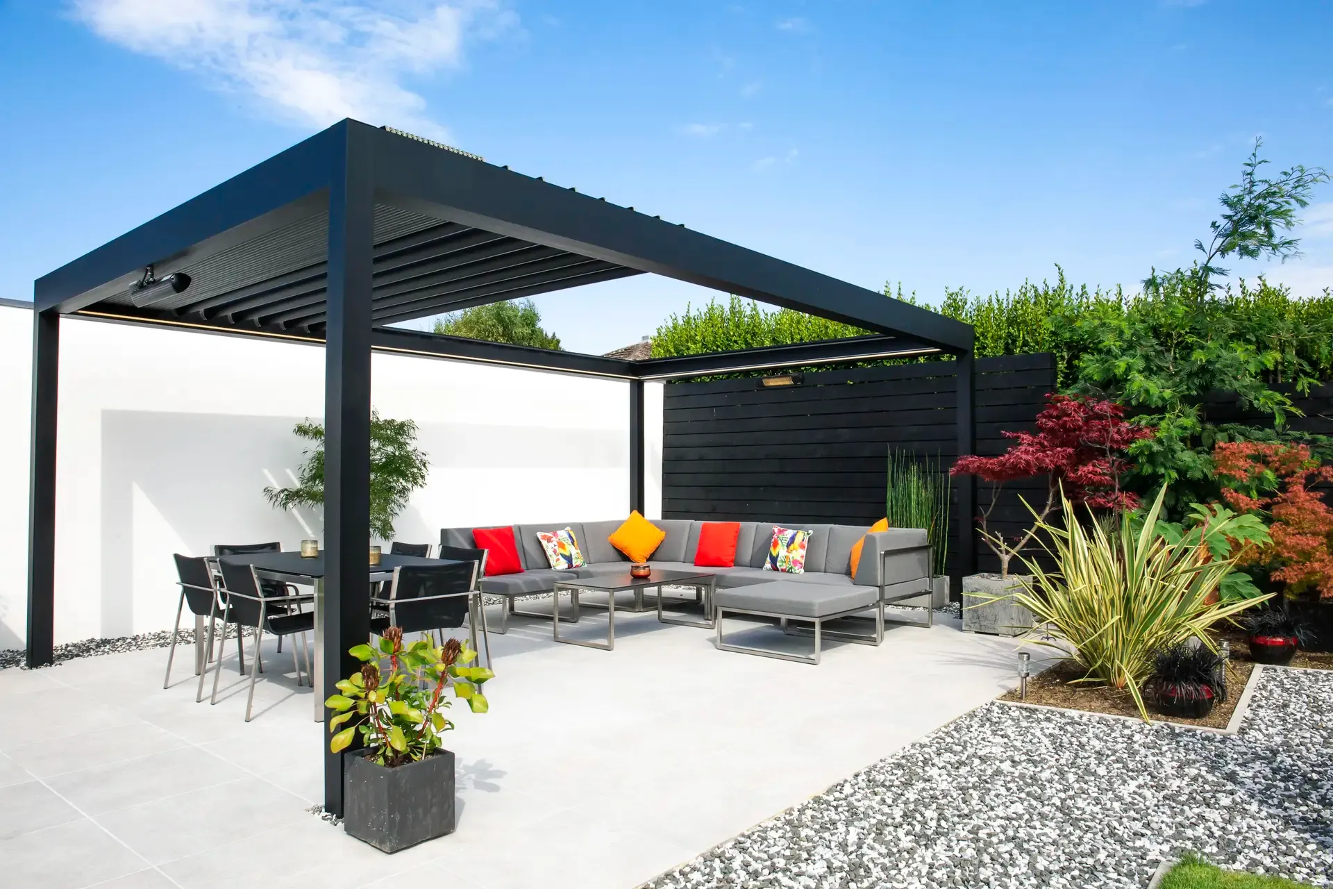 Anthrazitfarbenes Lamellendach B600 S über einer Terrasse mit Lounge und Essbereich im Garten