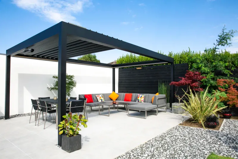 Anthrazitfarbenes Lamellendach B600 S über einer Terrasse mit Lounge und Essbereich im Garten