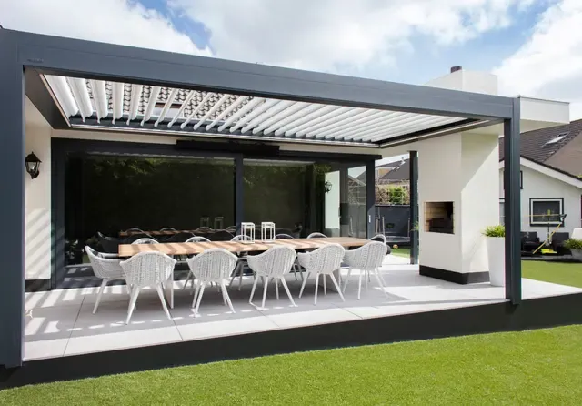 Lamellendach B600 S über einer grossen Terrasse mit Esstisch und Cheminée, Lamellen teils geöffnet