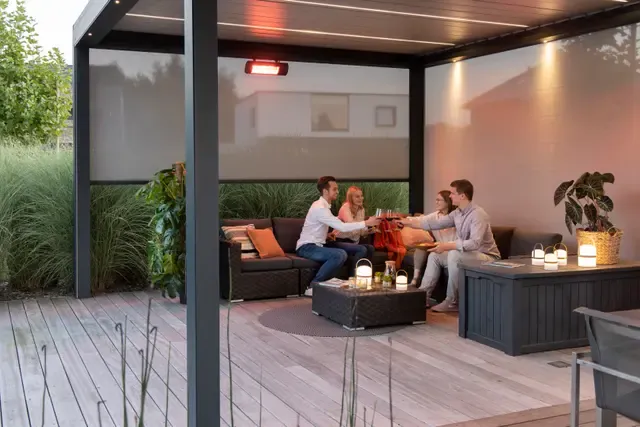 Infrarot-Terrassenheizung unter einem Lamellendach, darunter eine Sitzgruppe am Abend