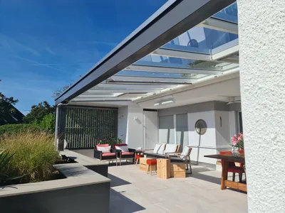 Pergola mit Glasdach über der Terrasse eines Seerestaurants.