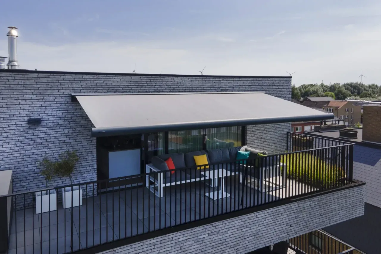 Grossflächen-Markise über einer Dachterrasse mit Loungebereich, im Hintergrund Häuser