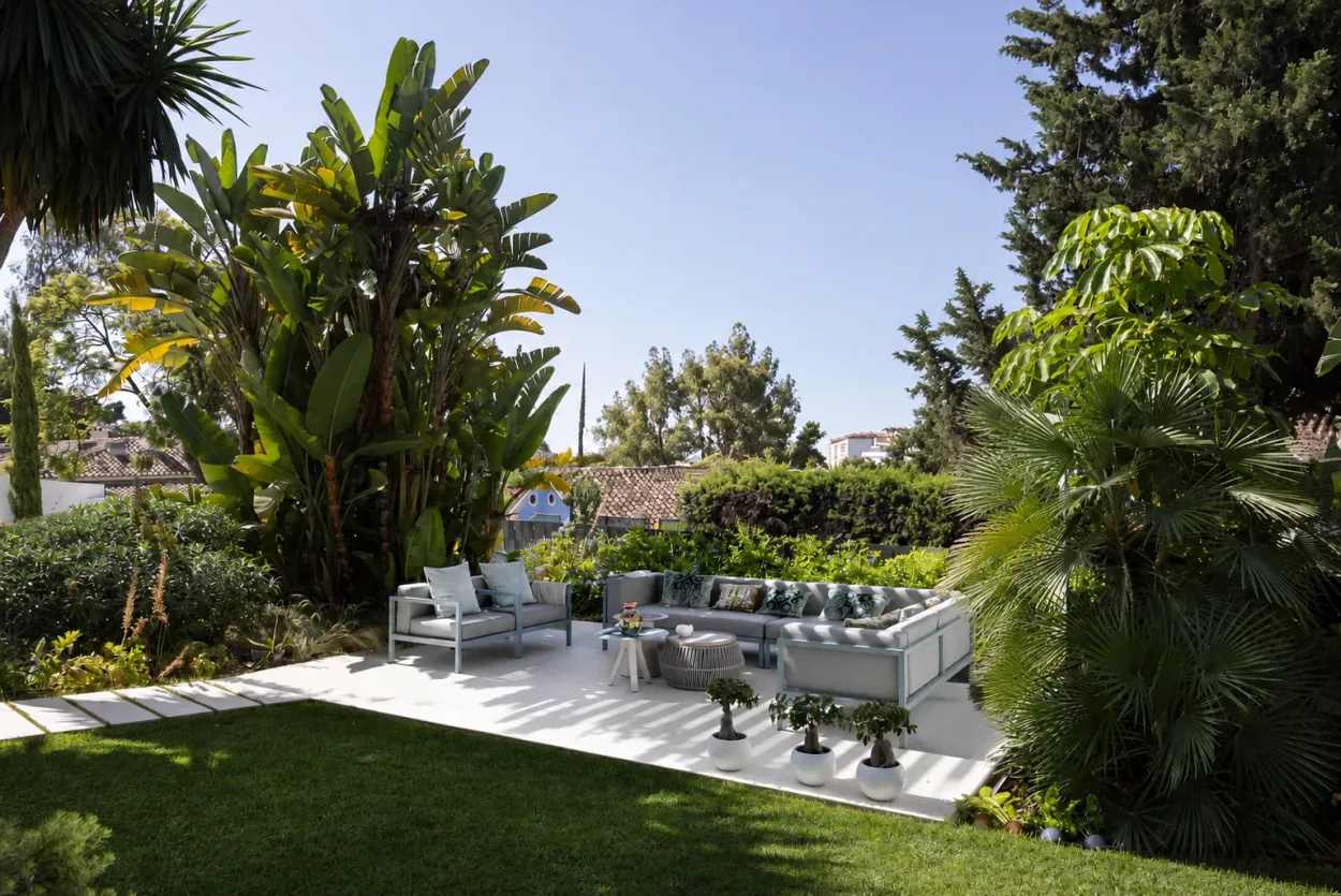 Offene Gartenterrasse mit Loungemöbeln in der Sonne, ohne Überdachung