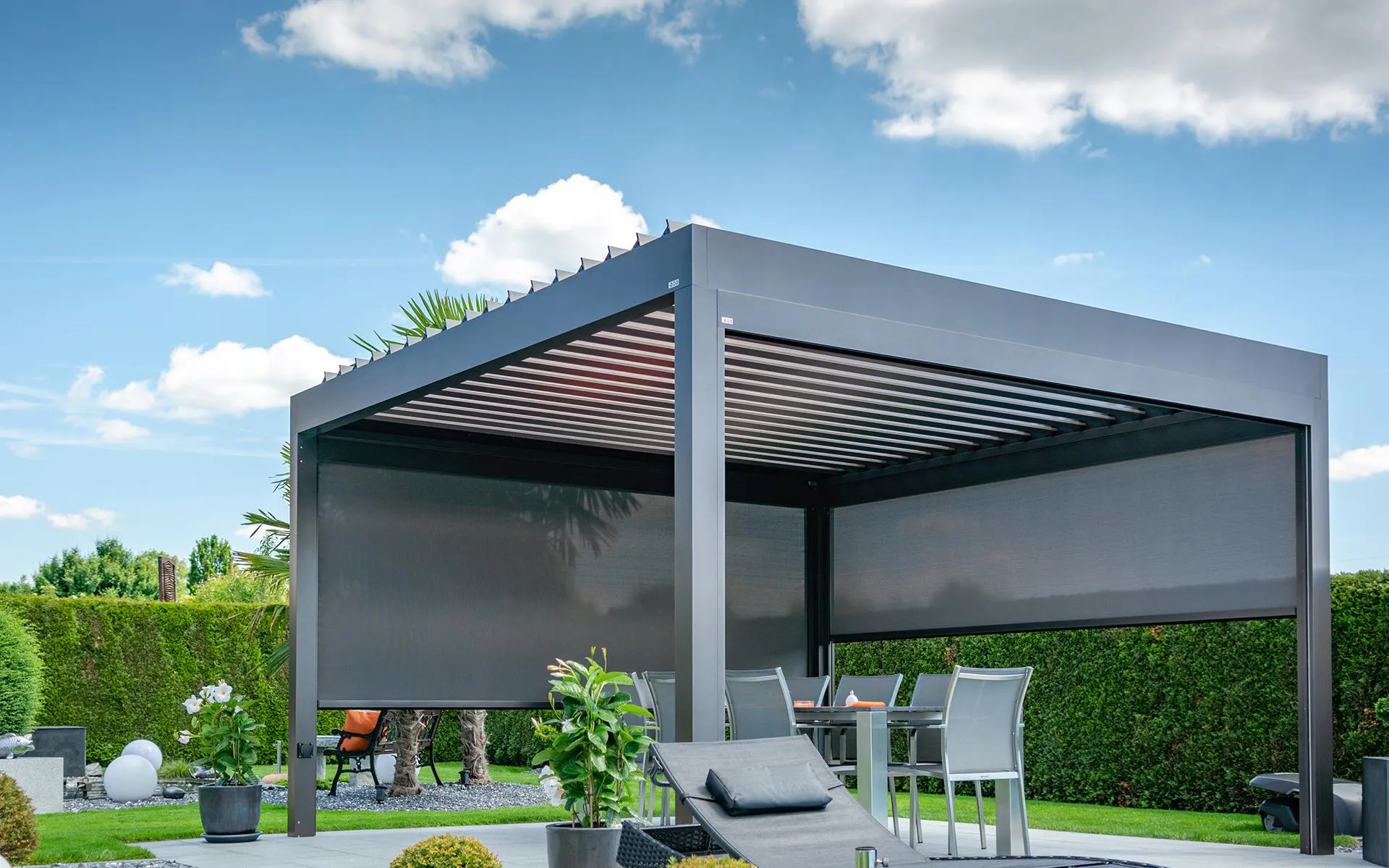 Pergola mit Lamellendach über einer Terrasse, Blick ins Grüne