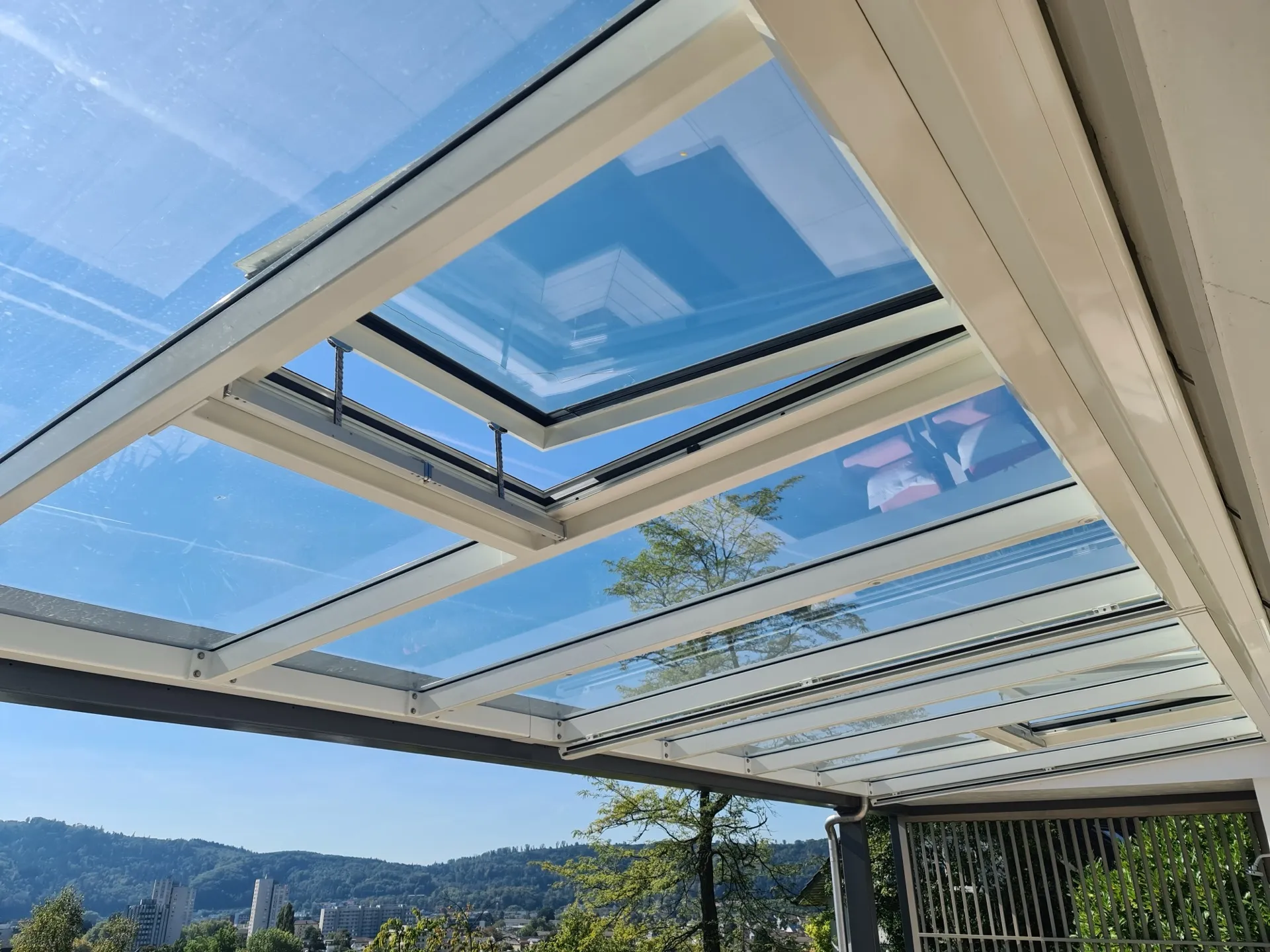 Pergola mit verglastem Schiebedach über einer Gartenterrasse bei Tageslicht
