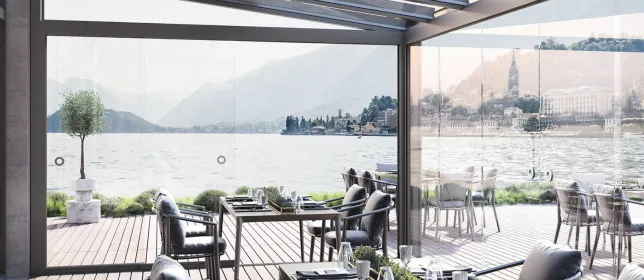 Restaurantgarten am Wasser mit Lamellendach, Tischen und Abendbeleuchtung