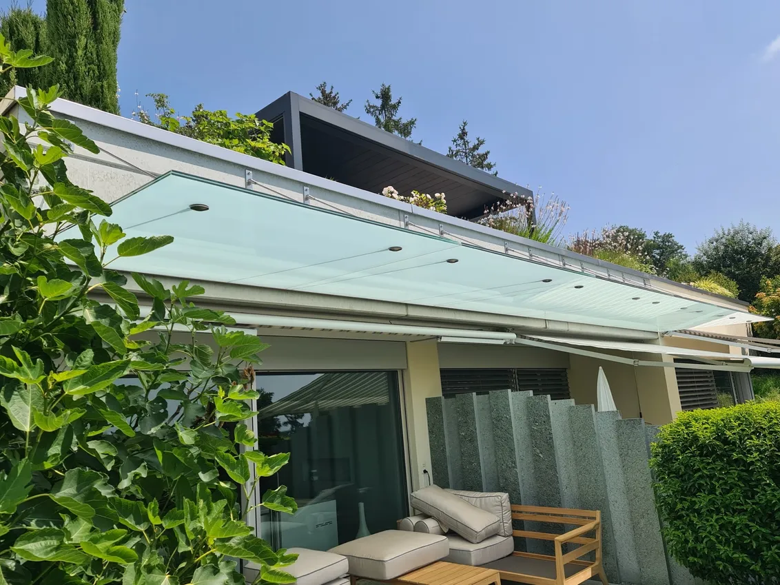 Schlankes Vordach aus Aluminium und Glas an einer hellen Fassade