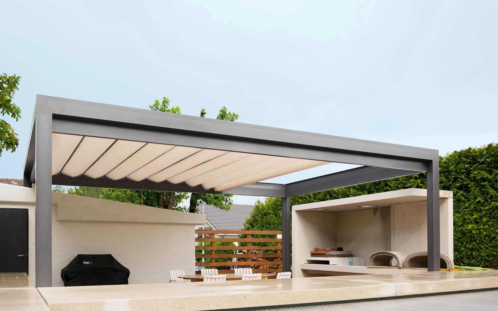 Anthrazitfarbene Pergola mit Lamellendach vor einem Wohnhaus